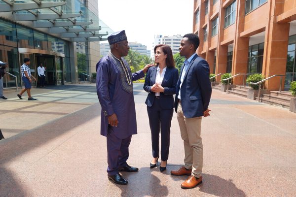 Nigerian elder man speaking with a young Nigerian man and an American woman