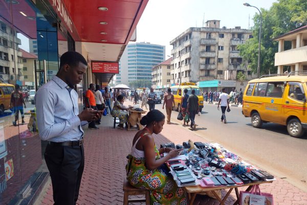 Nigerian man and woman in the street, the man is an office worker and the woman is a street vendor