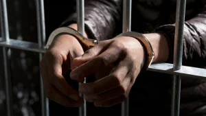 Handcuffed inmate behind bars