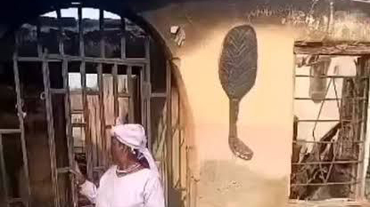 -Olorisa in front of the burnt building