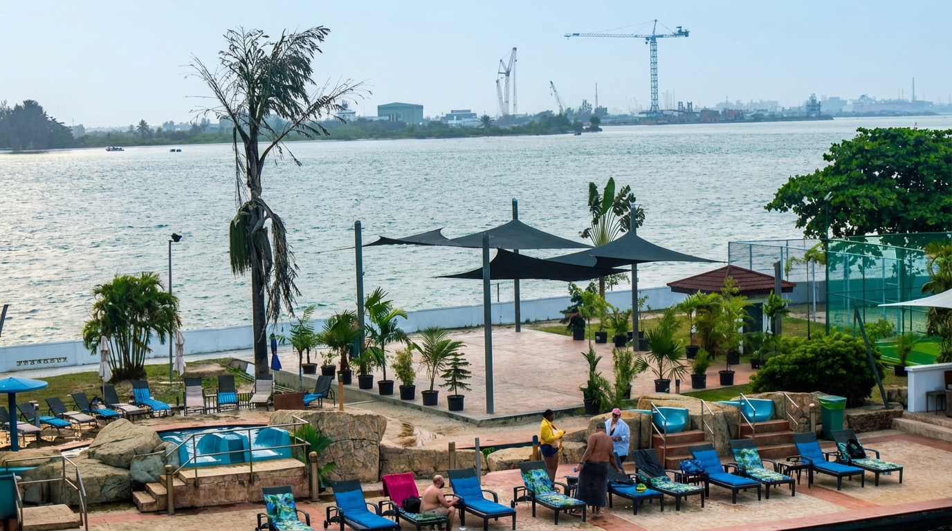 One of the waterfront leisure spaces at Federal Palace Hotel and Casino in Victoria Island Lagos, featuring poolside loungers, shaded seating, landscaped plants and views of the Lagos Lagoon with construction cranes in the distance