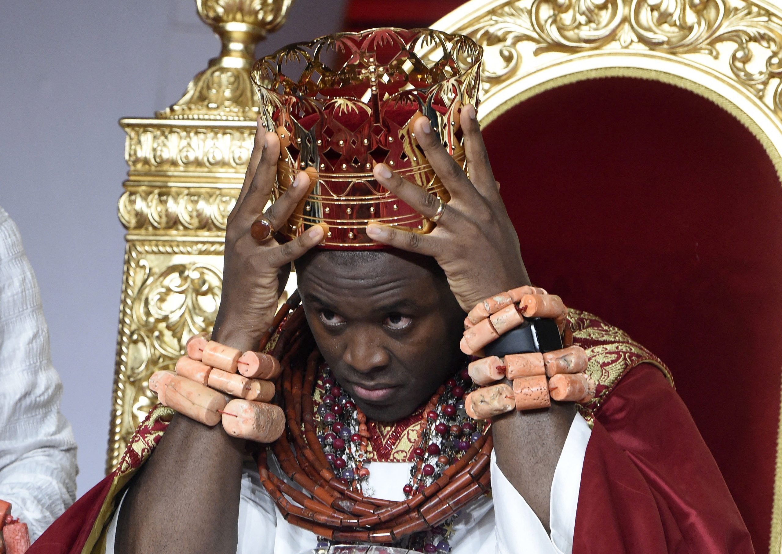 Prince Tsola Emiko adjusts his crown after being installed as the 21st Olu of Warri kingdom and the Ogiame Atuwatse 111 during his coronation at Ode Itsekiri on August 21, 2021. Thirty seven-year-old Prince Tsola Emiko, now the Ogiame Atuwatse 111, has been installed as the king or known as the Olu of Warri kingdom in Niger delta region, one of the foremost royal institutions in the country. Thousands of people in traditional red and white attire thronged to the riverine community of Ode-Itsekiri in southern Nigeria's oil hub Warri to witness the ascension of their new king. (Photo by PIUS UTOMI EKPEI / AFP)