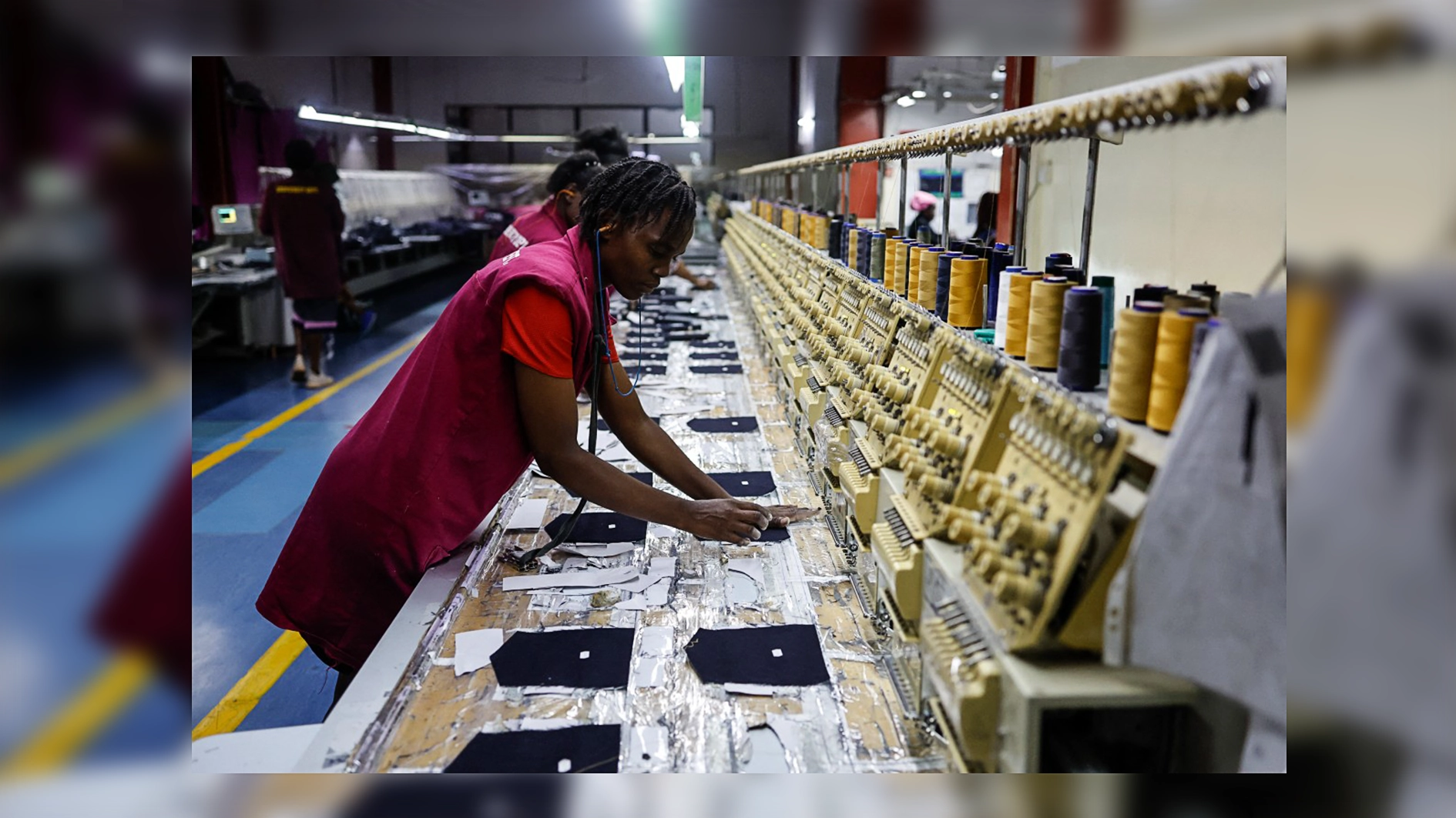 A worker operates an industrial embroidery machine inside the United Aryan textile factory