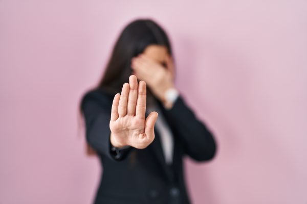 Young brunette woman wearing business style over pink background covering eyes with hands and doing stop gesture with sad and fear expression. embarrassed and negative concept.