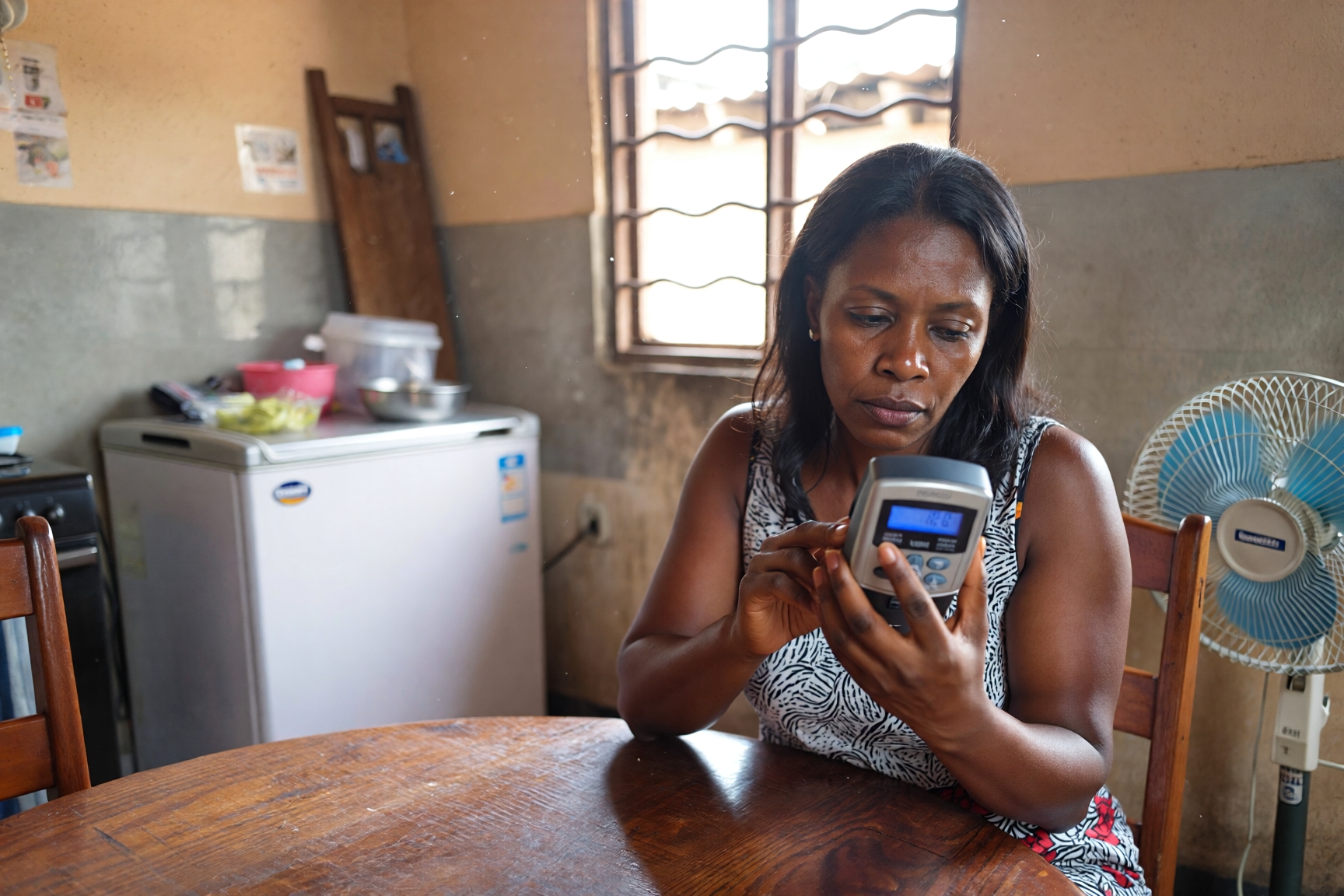 Nigerian woman reviewing electricity usage on a device in her kitchen, illustrating how many units home appliances consume in Nigeria