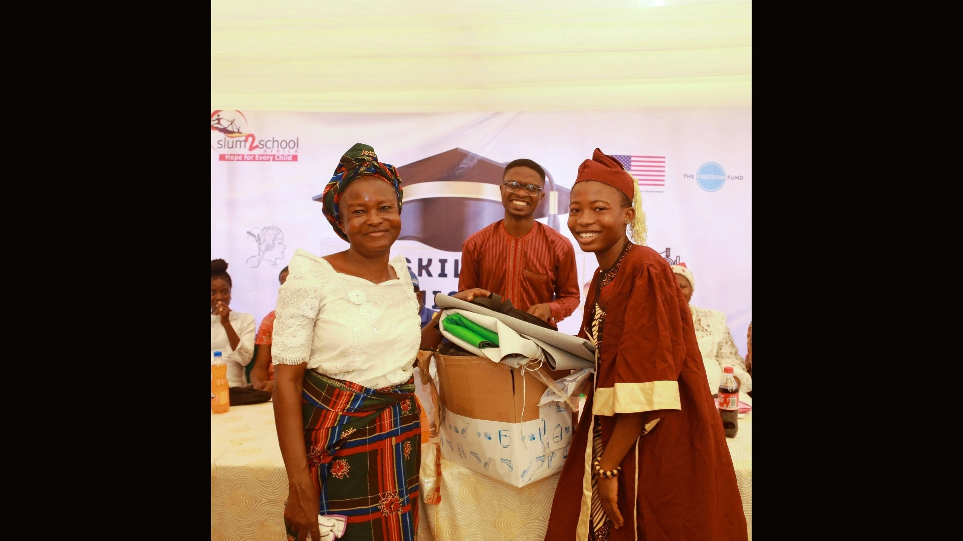 A guardian, a representative of a partner organization, and a beneficiary showing excitement during the CDW graduation ceremony and presentation of starter packs.