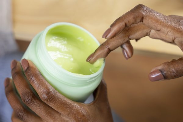 high-angle-hand-holding-cream-container