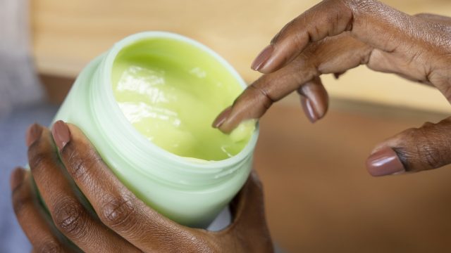 high-angle-hand-holding-cream-container