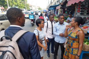 Young West African professionals in a city market discussing nationality identity and the difference between being Nigerien and Nigerian