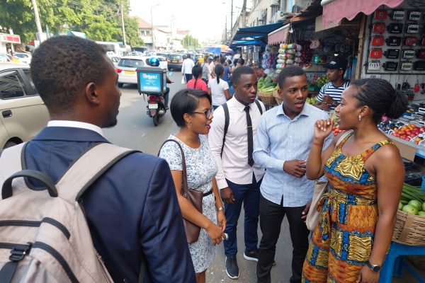 Young West African professionals in a city market discussing nationality identity and the difference between being Nigerien and Nigerian