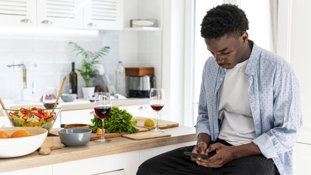 nigerian-man-using-phone-kitchen-healthy-food.jpg