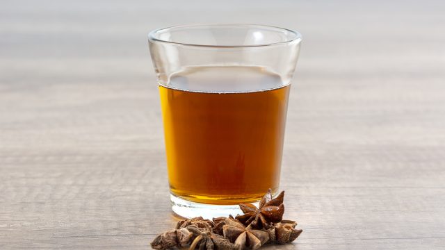 Closeup of a glass of tea with star anise on a wooden surface with a blurry background
