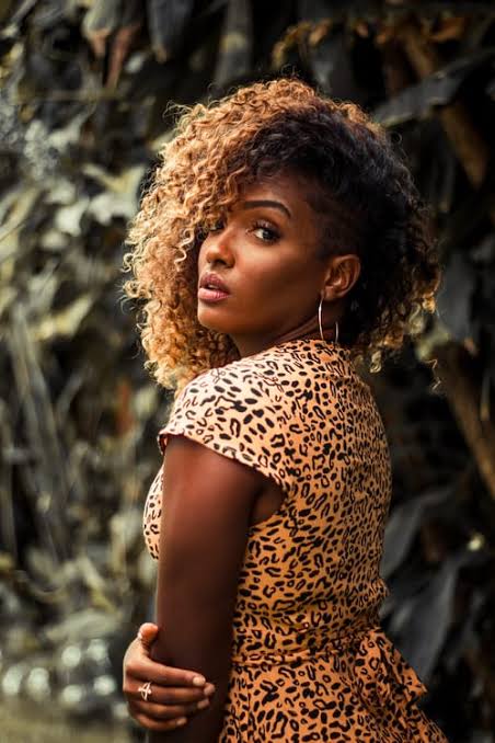 Woman with curly afro hair in caramel balayage wearing a leopard print dress