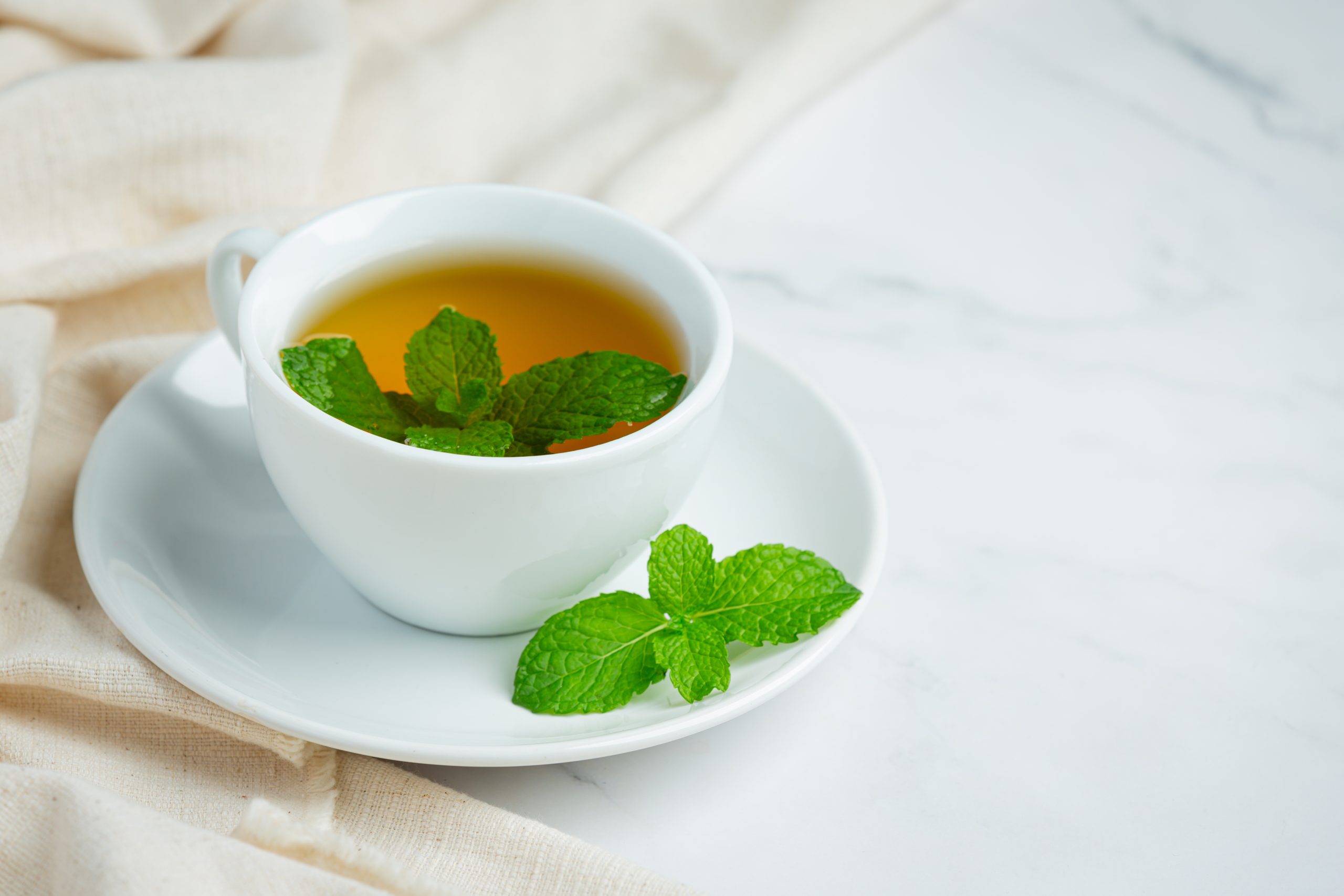 A warm cup of Peppermint tea served in a ceramic mug, known for its calming properties, soothing aroma, and potential wellness benefits.