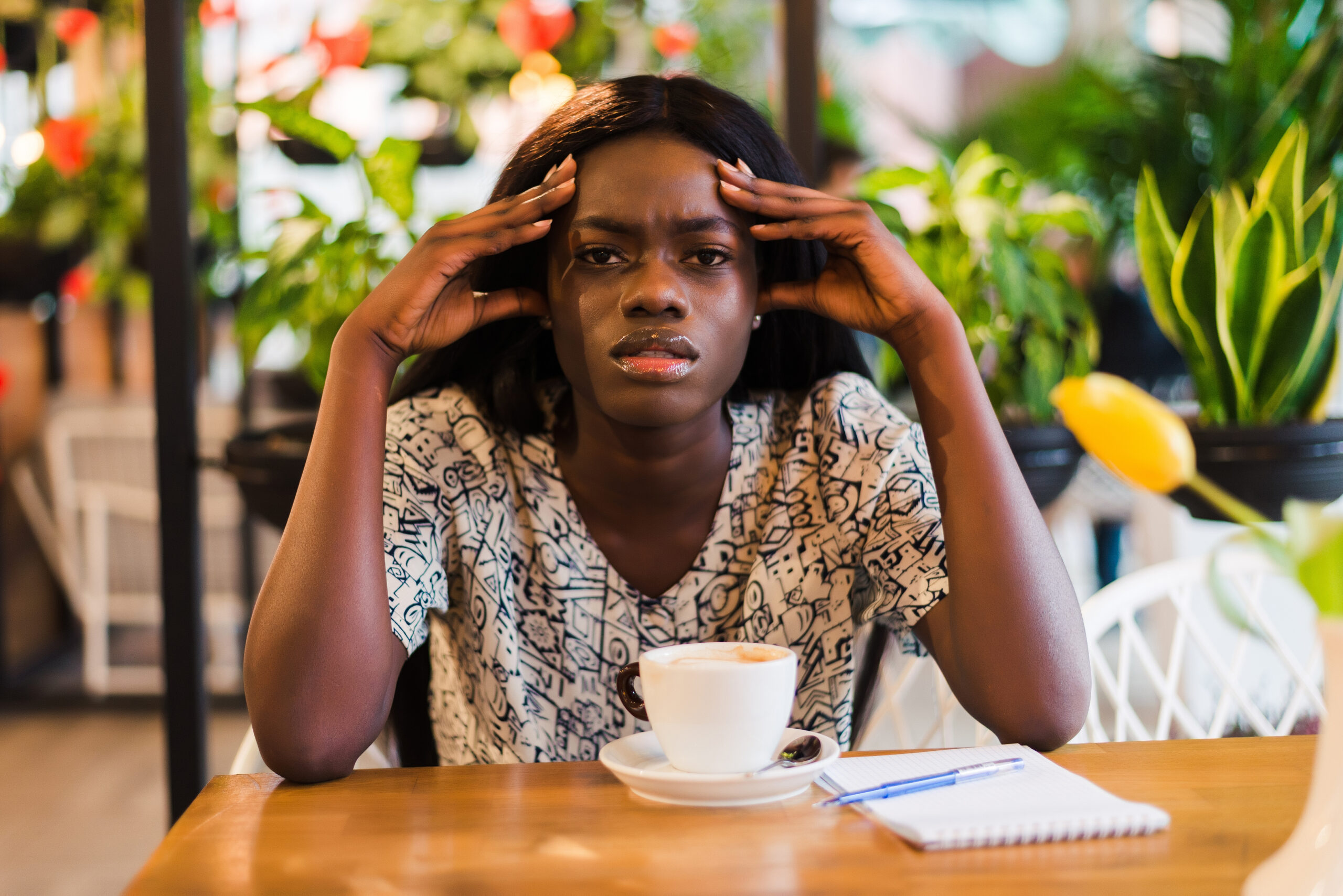 Young woman with coffee cup having headache in cafe